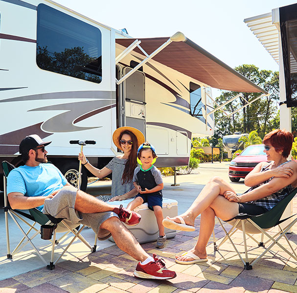 Young family sitting outside RV